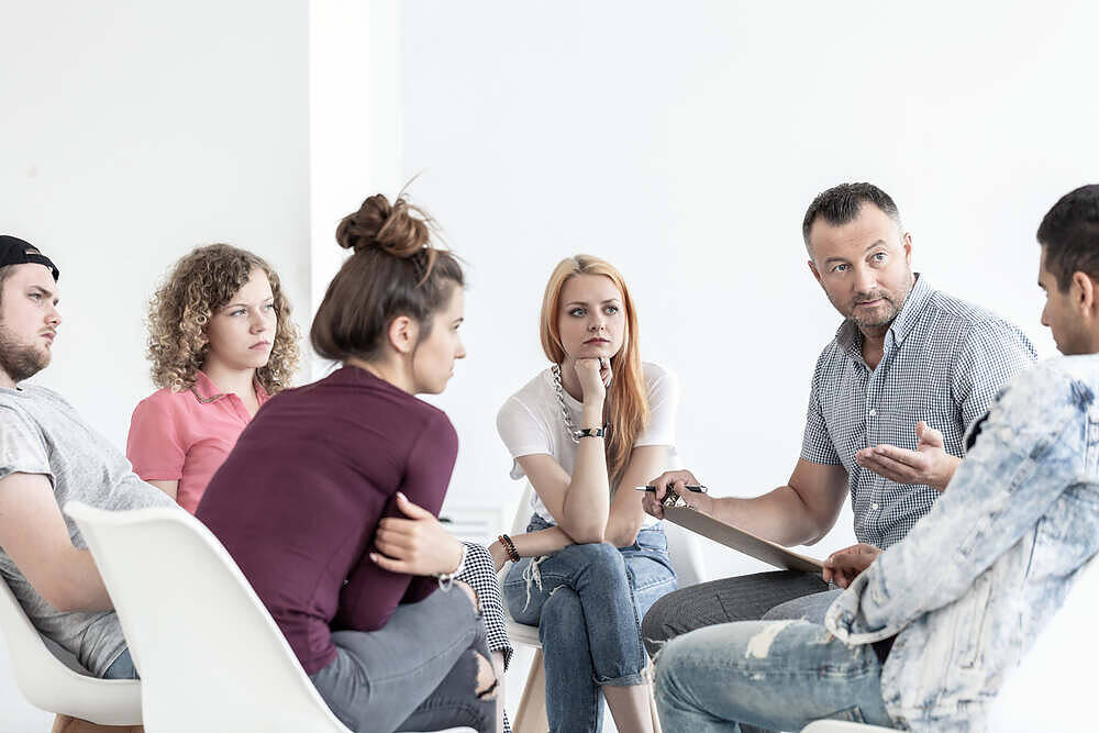 School counselor explaining anger management techniques to a group of teenagers during a session.
