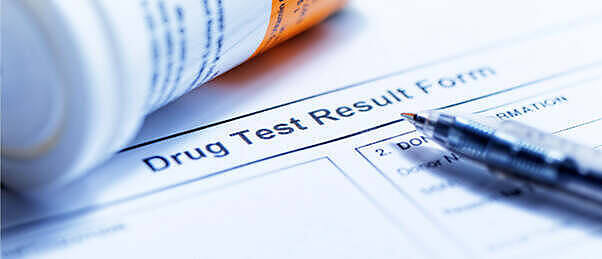 Close-up of a drug test result form with a pen, illustrating the process of documenting marijuana detection periods in various drug tests