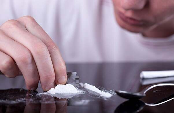 cocaine or other drugs cut with razor blade, hand dividing white powder narcotic