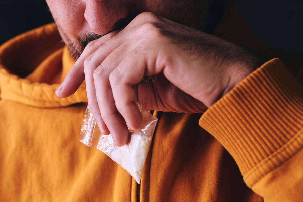 Man contemplating holding a cocaine baggie