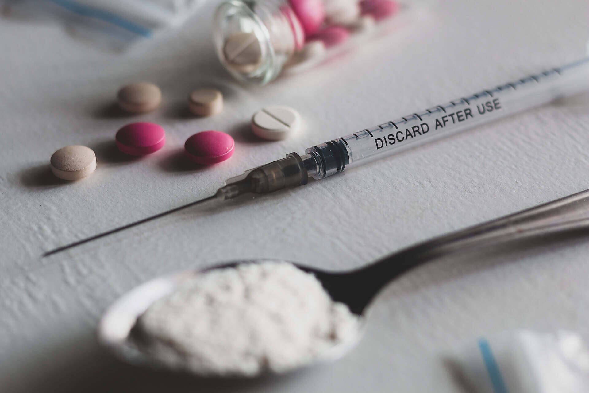 Various drugs including pills, powder, and a syringe for injection, illustrating different forms of substance abuse
